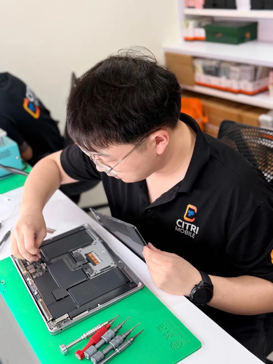 Citri Mobile technician repairing a MacBook logic board on the bench at our Singapore workshop